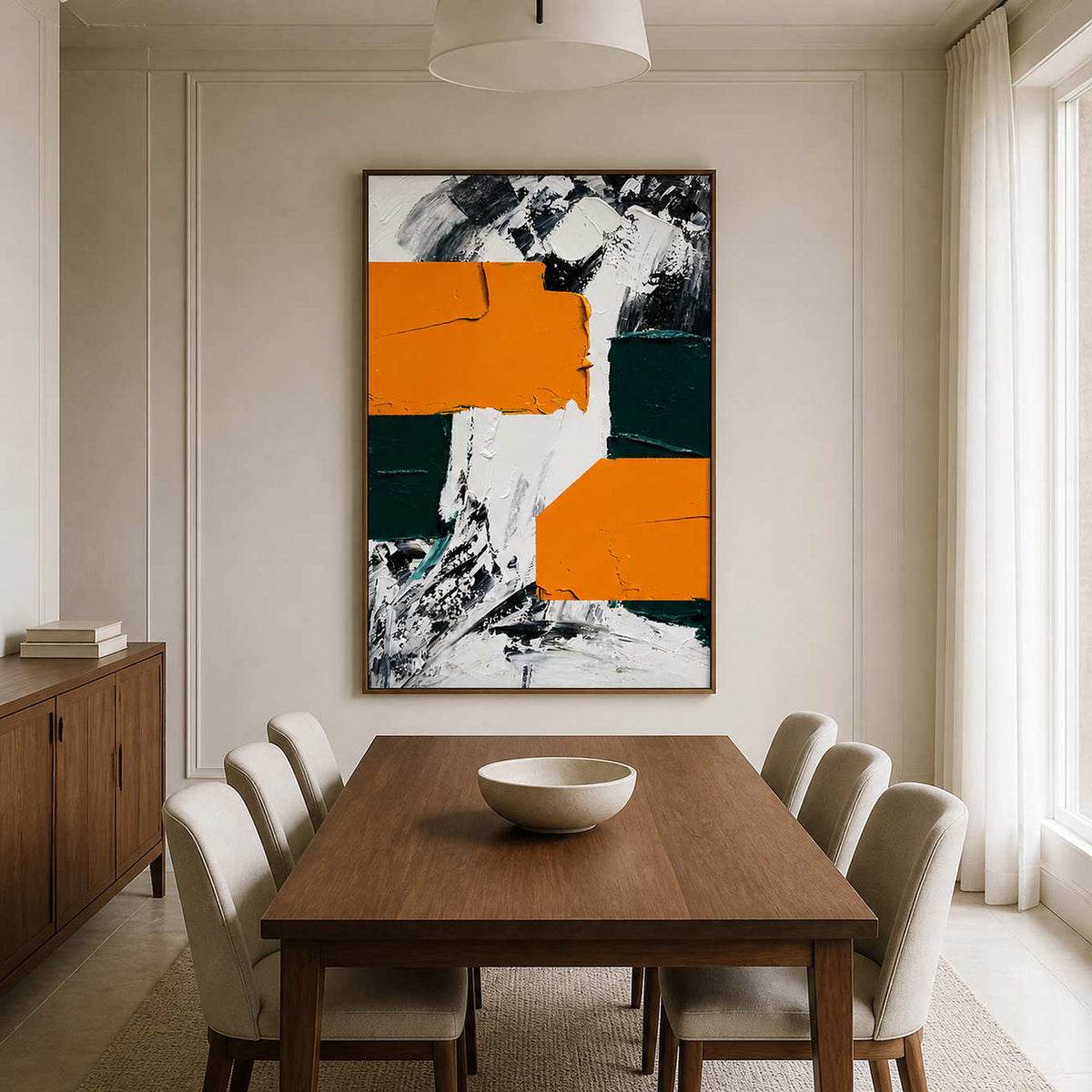 Wood framed orange and green abstract painting beside a long wooden dining table.