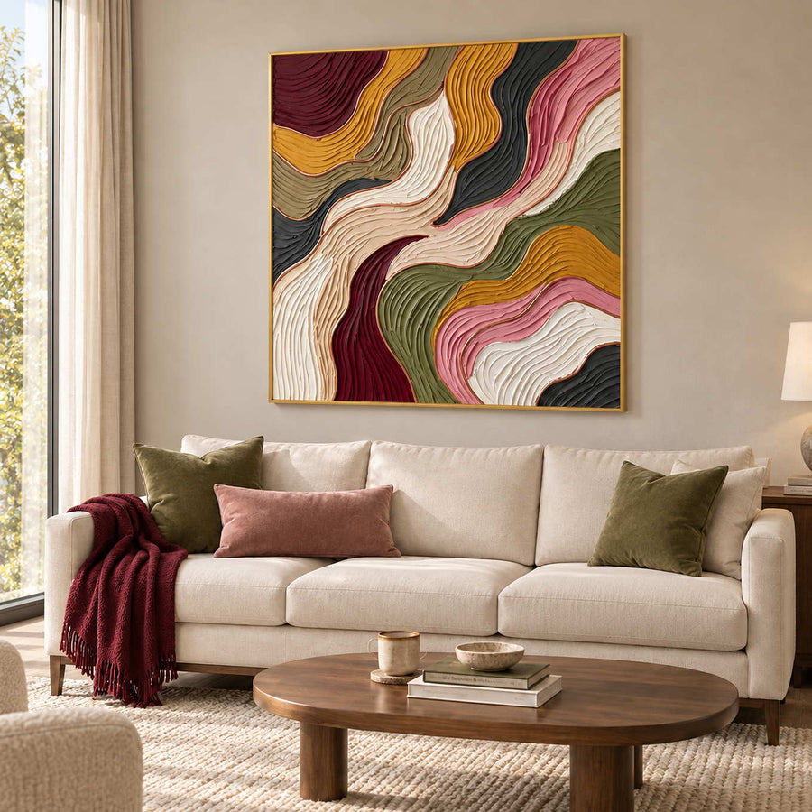 Love in Motion in a gold frame above a cream sofa with olive and pink cushions and a burgundy throw.