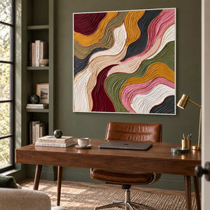 Love in Motion in a white frame above a wood desk and brown leather chair against a deep olive wall.