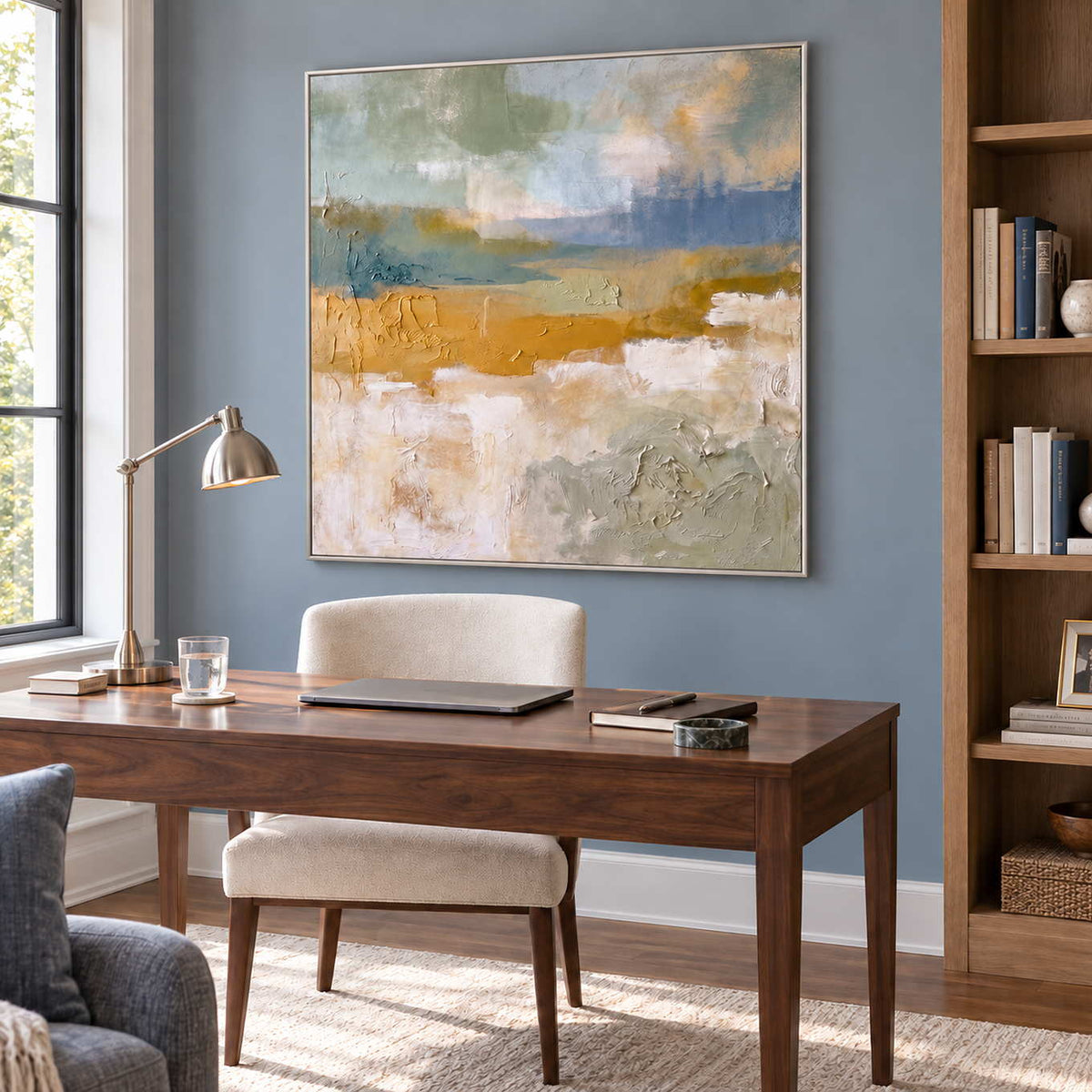 Meeting the Open Country in a silver frame above a wood desk and cream chair against a muted blue wall.