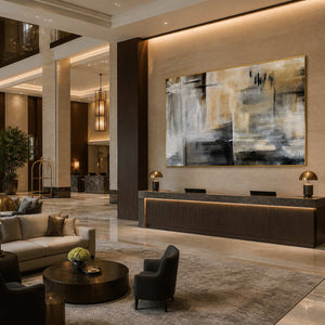 Gold framed horizontal abstract artwork above a hotel reception counter in a spacious lobby.