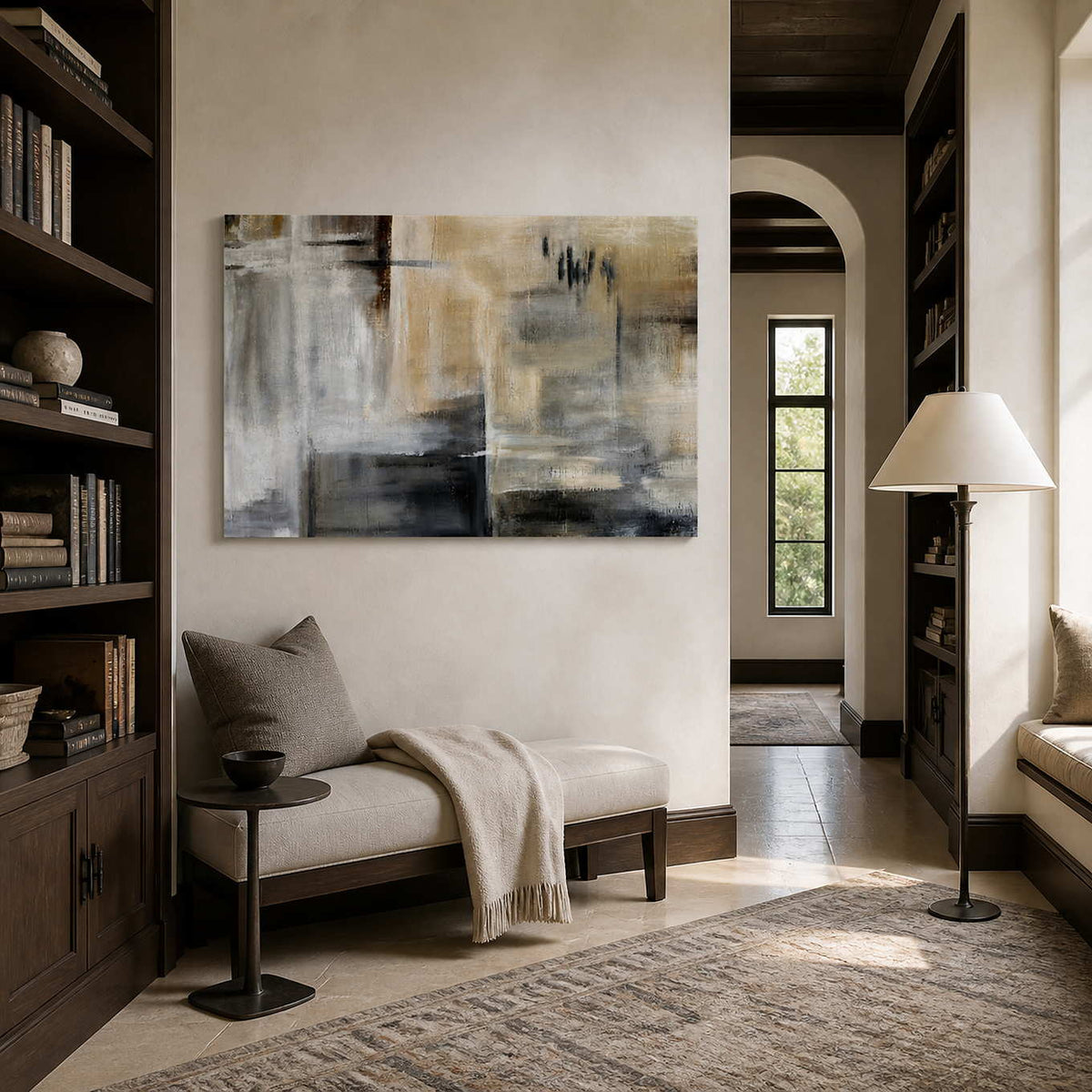 Frameless gray and sandy painting above a cushioned bench between reading gallery bookshelves.