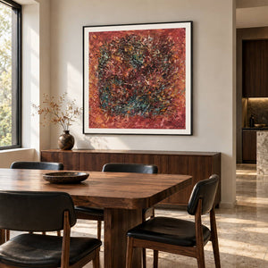 Artwork showing a dark textured ring surrounded by rust red and orange with scattered turquoise flecks in a dining area beside the table, with a black frame.