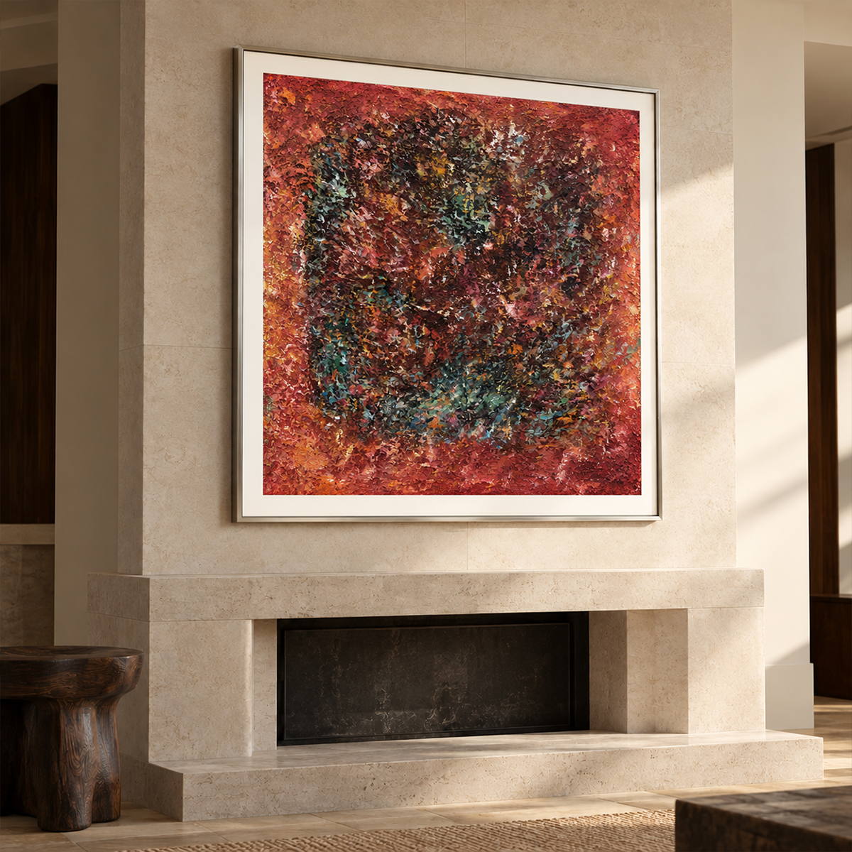 A dark textured ring surrounded by rust red and orange with scattered turquoise flecks in an artwork with a silver-colored frame, displayed above a fireplace.