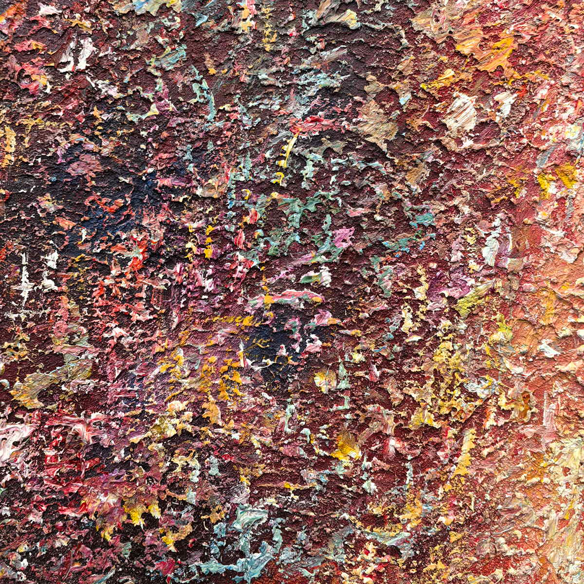 Close-up of rust-red, dark brown and turquoise fragments across a rough raised surface.