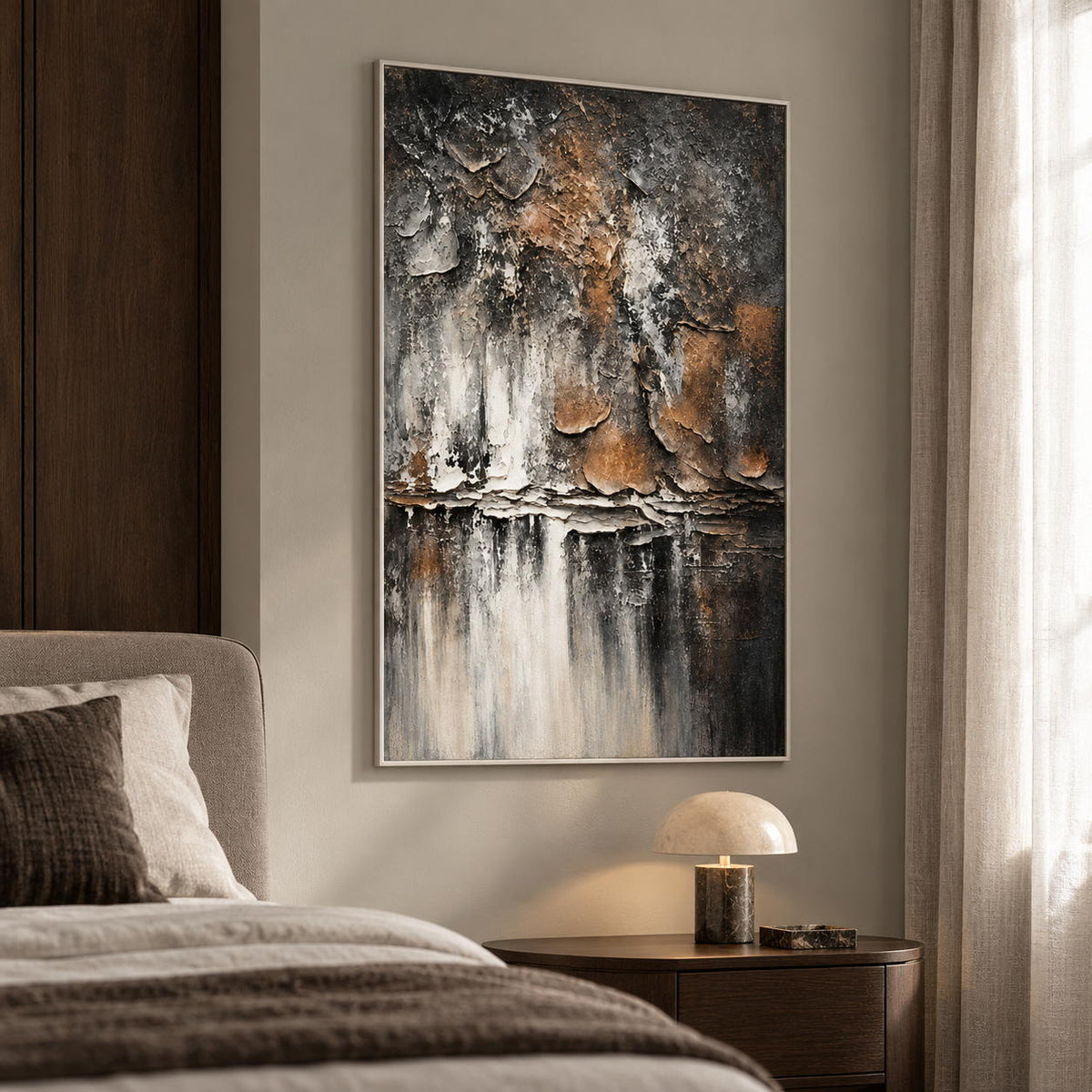 In a bedroom near the bed, an artwork with a white frame shows dark gray and brown flaking forms above horizontal strata and pale vertical streaks.