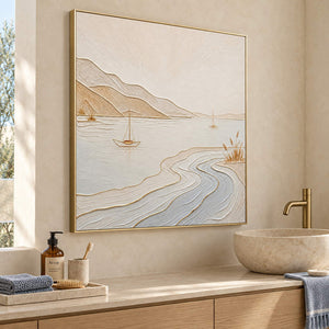 Pale coastal painting with sailboats, sandy hills, and curving wave contours in a gold frame beside a bathroom vanity.