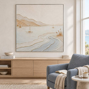 Pale coastal painting with sailboats, sandy hills, and curving wave contours in a silver frame in a reading room.