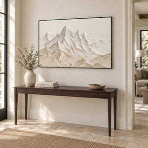 Mountains Keeping Watch in a black frame above a slim dark wood entryway console and ceramic vase.