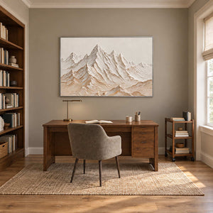 Mountains Keeping Watch in a silver frame above a wood desk and taupe chair beside bookshelves.