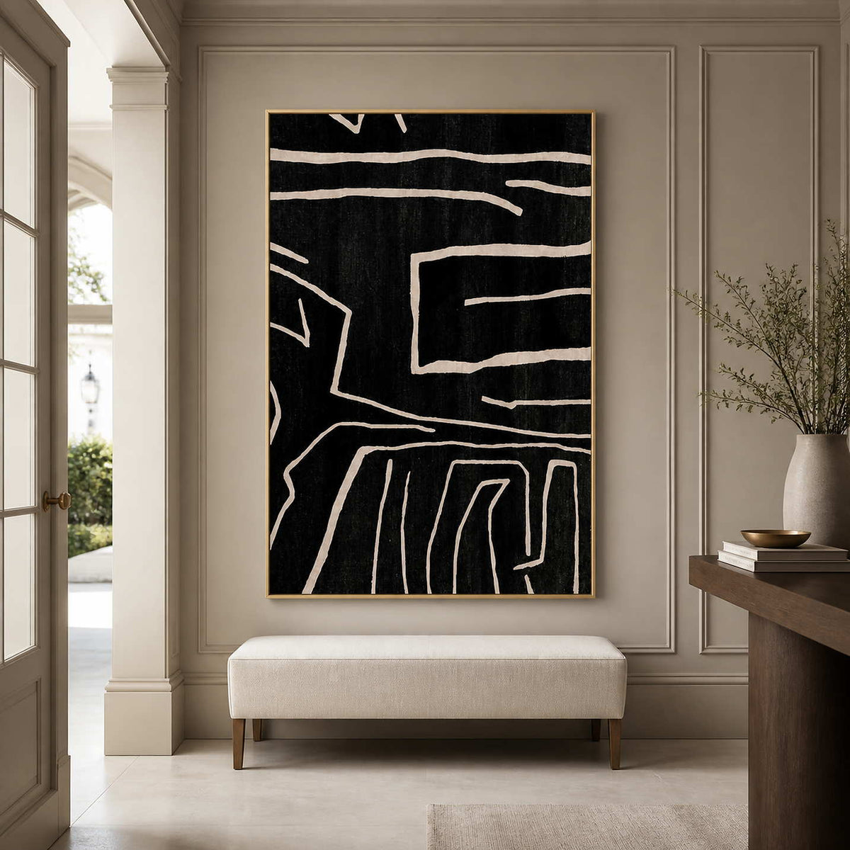 Gold framed abstract line painting above a cream bench in a paneled entryway.