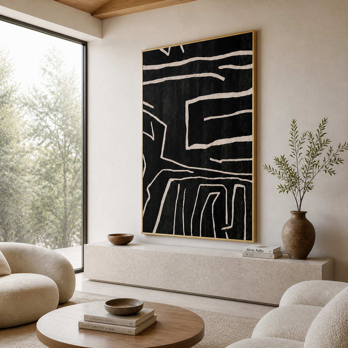 Black abstract line painting in a gold frame beside curved cream seating.