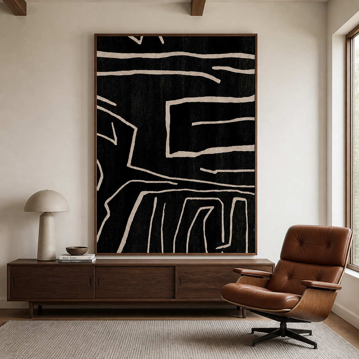 Wood framed black abstract painting beside a brown leather reading chair.