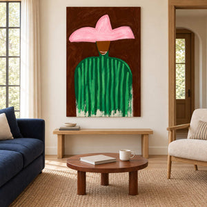 Pink-hat portrait above a wooden bench between a navy sofa and a cream armchair.