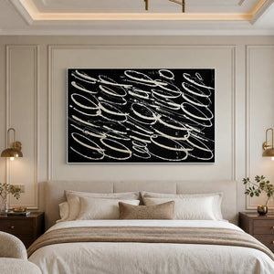 White framed black abstract painting above a cream upholstered bed.
