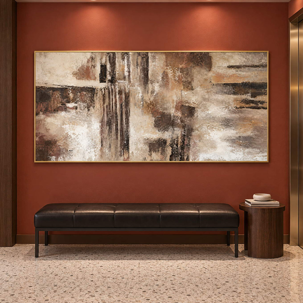 Hand-painted abstract wall art in ivory, taupe, umber, and charcoal, displayed in a hotel elevator lobby in a gold frame.