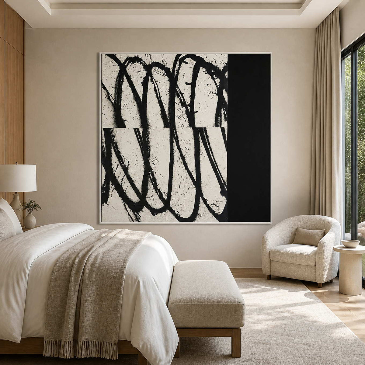 White framed black and white abstract artwork beside a bed and cream bedroom reading chair.