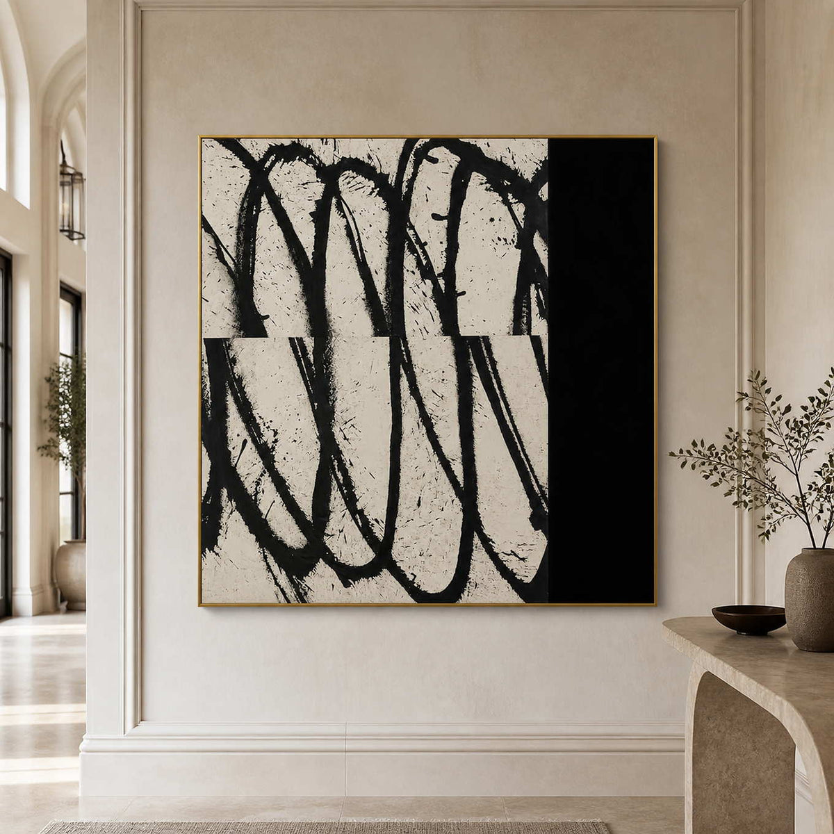 Gold framed black and white abstract artwork beside a stone console in an arched hallway.