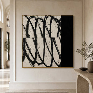 Gold framed black and white abstract artwork beside a stone console in an arched hallway.