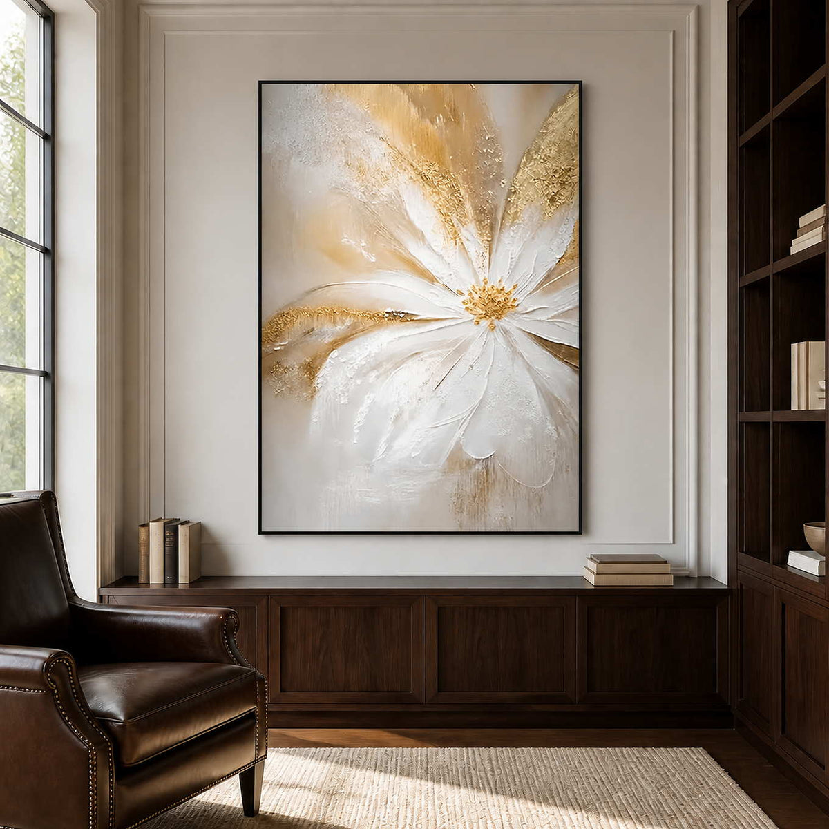 One Bloom of Joy in a black frame above a low wood cabinet beside a leather reading chair and bookshelves.