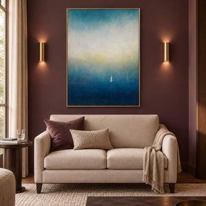 Atmospheric coastal painting with a white sail drifting across deep teal water, displayed in a hotel lounge in a gold frame.