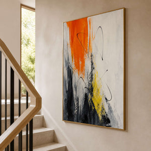 Vertical orange artwork displayed beside a warm modern stairway.