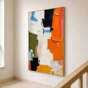 Vertical colorful abstract canvas displayed beside a light wood staircase.