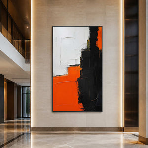 Bold orange and black abstract painting displayed in a contemporary hotel lobby.