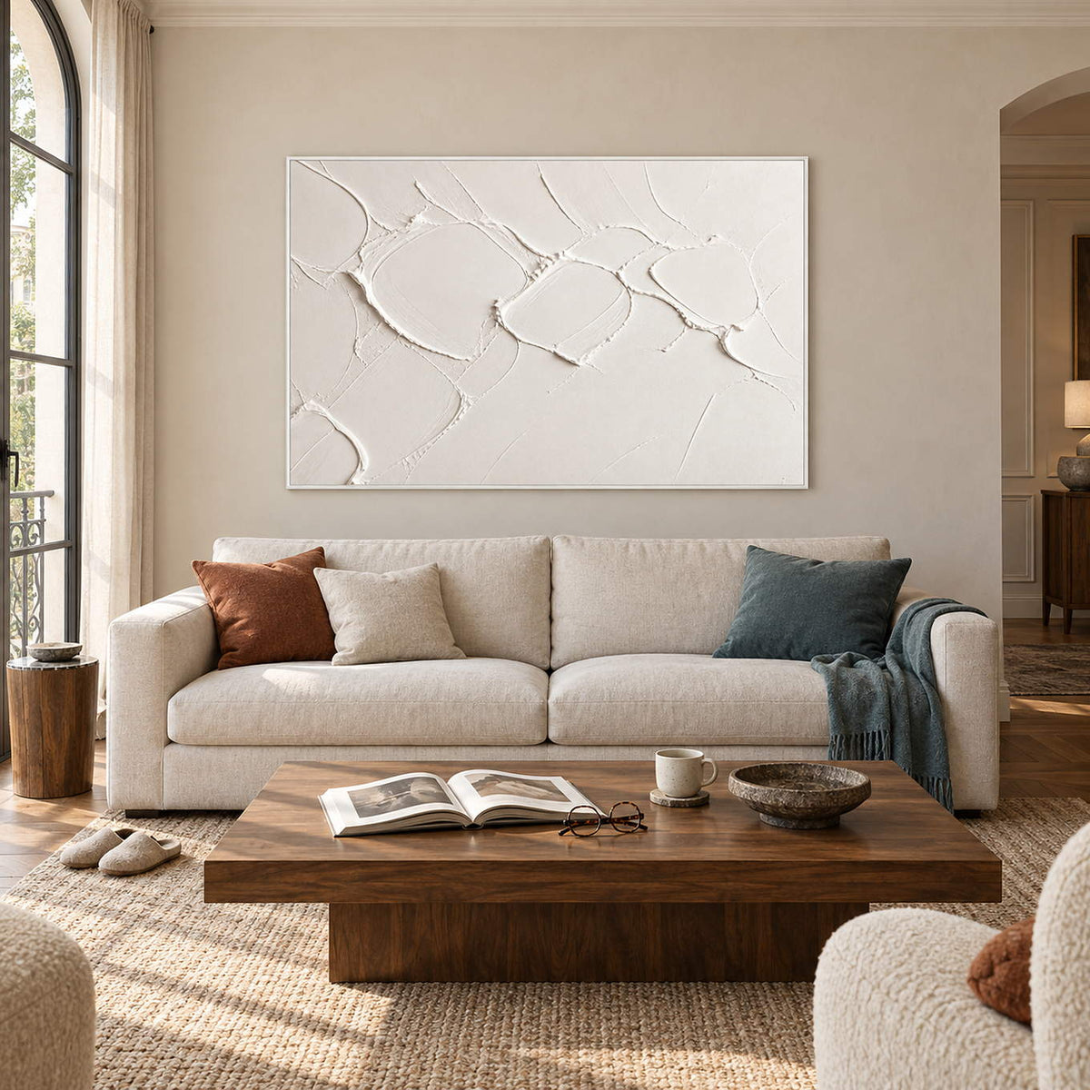 Chalk-white abstract relief painting with raised irregular seams in a white frame in a living room.