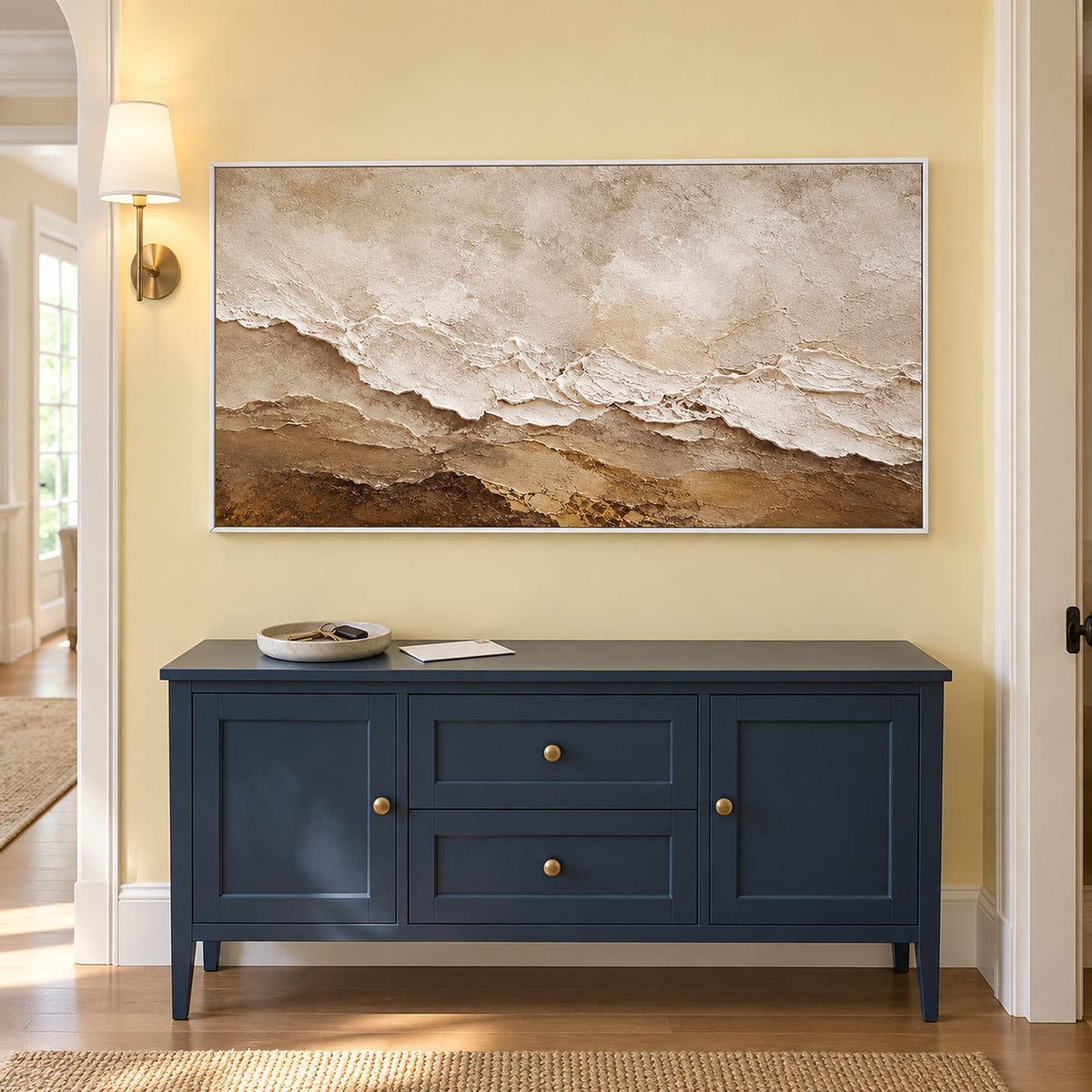 Hand-painted ivory, beige, and brown textured abstract canvas, displayed in a hallway in a white frame.