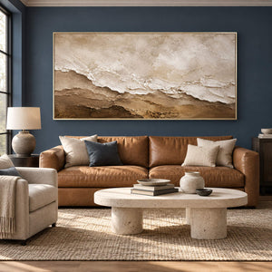 Hand-painted ivory, beige, and brown textured abstract canvas, displayed in a living room in a gold frame.