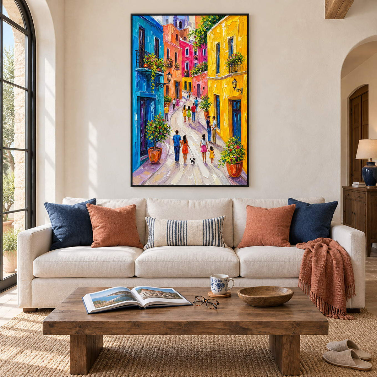 Colorful street painting with people, bright facades, and flowered balconies in a black frame in a living room.