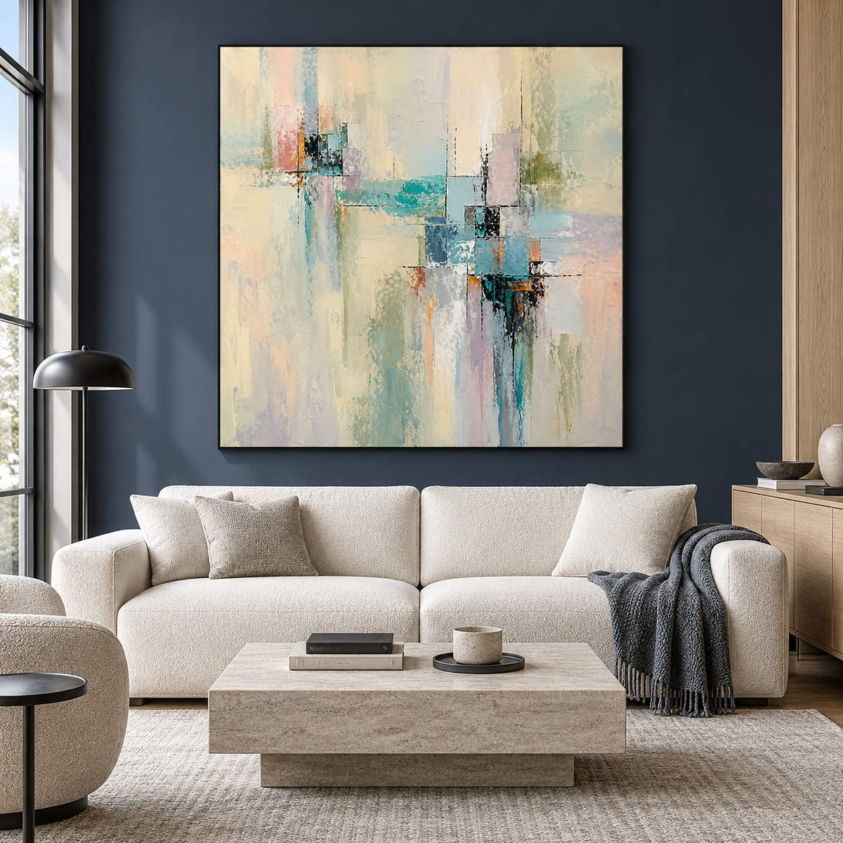 Hand-painted geometric abstract canvas in aqua, yellow, blush, and charcoal, displayed in a living room in a black frame.