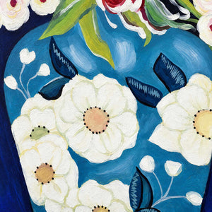 Close-up of white painted flower motifs and dark leaves on the blue vase.