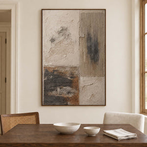 Weathered ivory and beige textures with gray blocks and dark marks in a brown wood frame, displayed above a dining table.