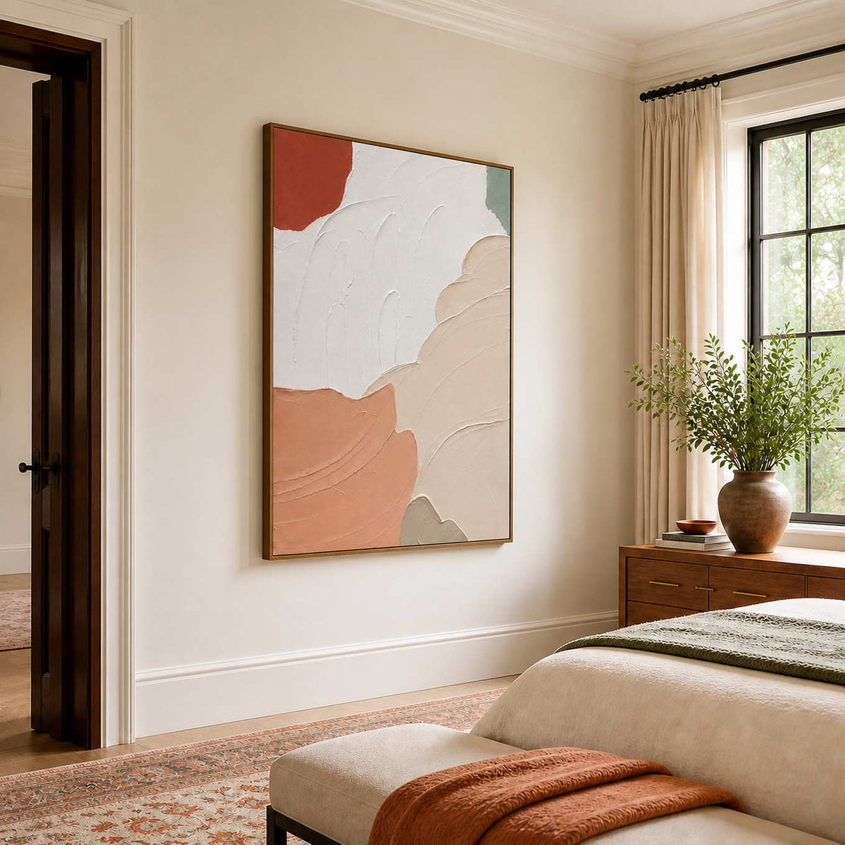 Wood-framed peach and white abstract artwork beside a bed with green and rust textiles.