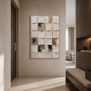Raised cream grid painting in a champagne gold frame near entryway wood cabinetry.