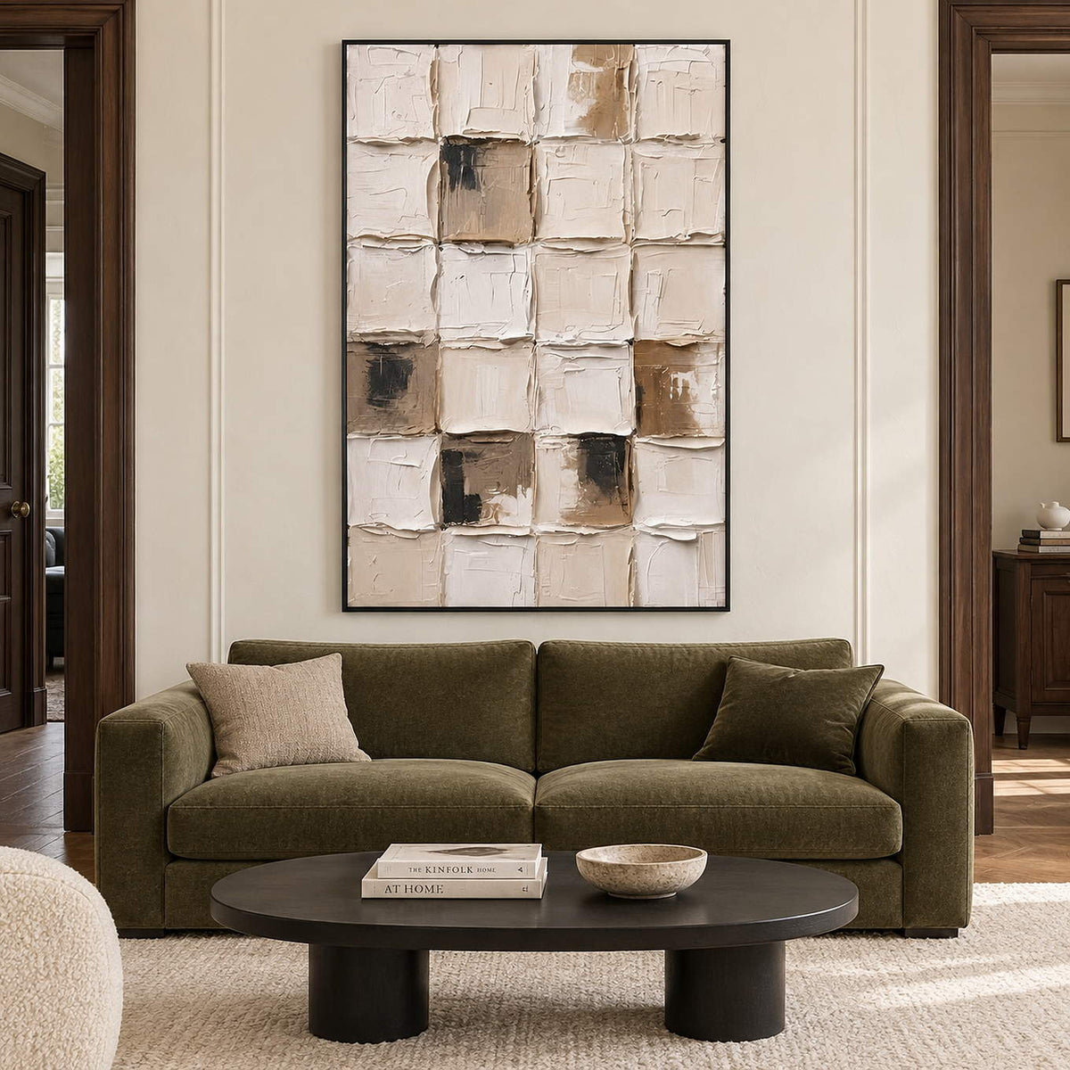 Raised cream grid painting with taupe and black patches in a black frame in a living room.