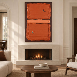 Orange block sports artwork above a lit pale fireplace in a cream-paneled room.