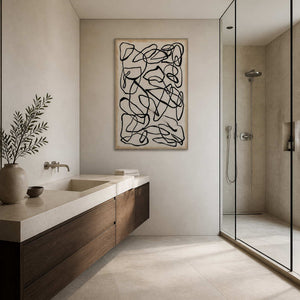 Cream and black abstract lines beside a wooden bathroom vanity and glass shower.