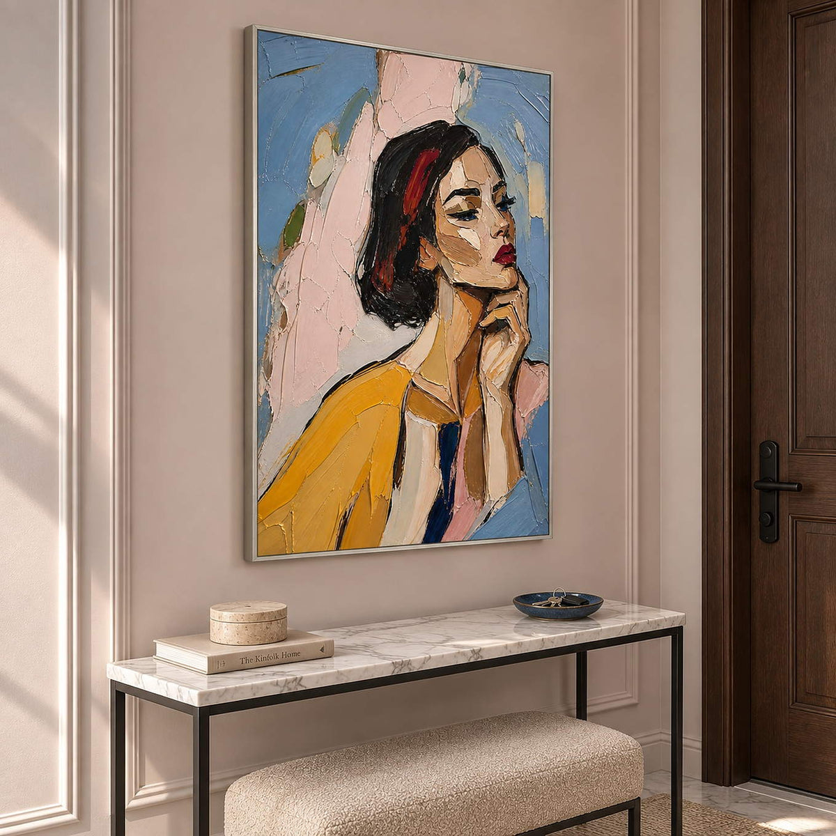 Textured portrait of a dark-haired woman in mustard yellow in a silver frame in an entryway.