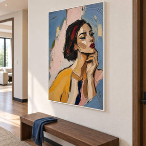 Textured portrait of a dark-haired woman in mustard yellow in a white frame in a hallway.