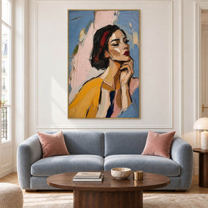 Textured portrait of a dark-haired woman in mustard yellow in a gold frame in a living room.