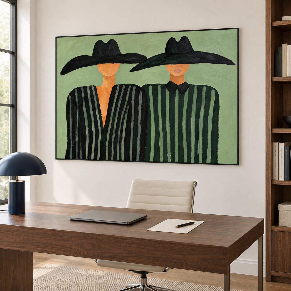 Two-hat artwork above a wooden desk beside a window.