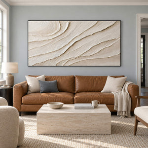 Panoramic ivory abstract wall art with layered flowing relief, displayed in a living room in a black frame.