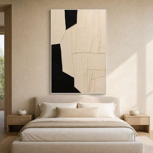 White framed cream and black abstract artwork above a softly upholstered bed.