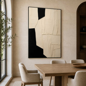 Black framed cream geometric artwork beside a wooden dining table and upholstered chairs.