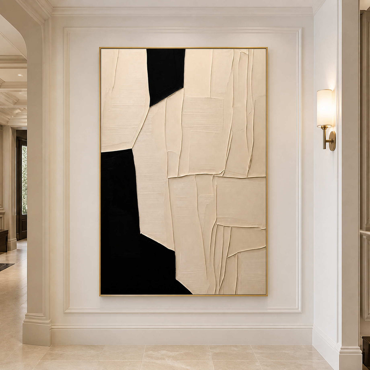 Gold framed cream and black abstract artwork beneath a wall light in a hallway.