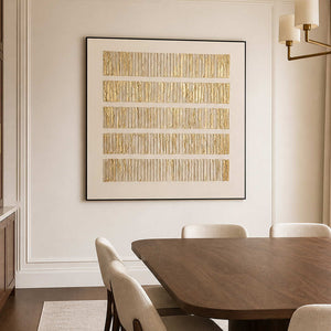 Black framed gold and cream abstract artwork beside a wooden dining table.