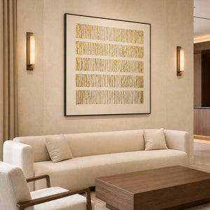 Black framed gold ridged artwork above a cream sofa in a hotel lobby.